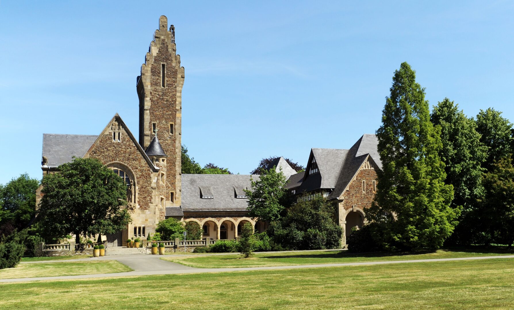 Die Kapelle des Südfriedhofs, davor grüne Wiese und darüber knallblauer Himmel.
