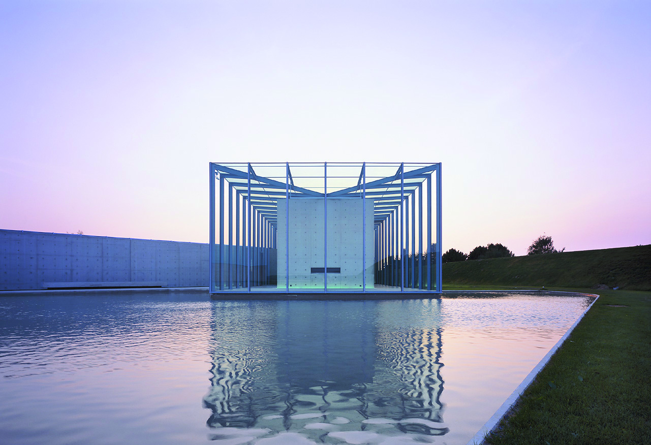 Düsseldorfer Museen: Langen Foundation, man sieht das Gebäude vor lilarosa Abendhimmel, im Vordergrund eine Wasserfläche, die das spiegelt.