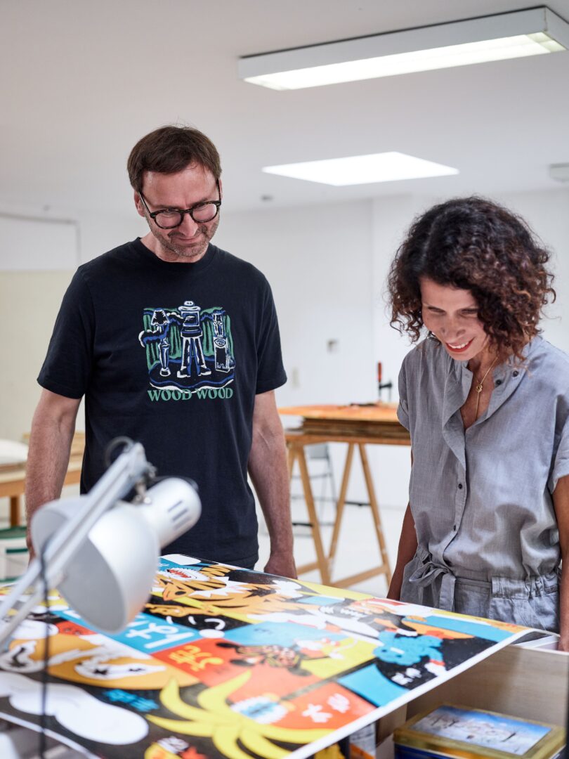 Roman Klonek und Ilona Marx betrachten einen Druck, den Roman Klonek während des Atelierbesuchs gefertigt hat.