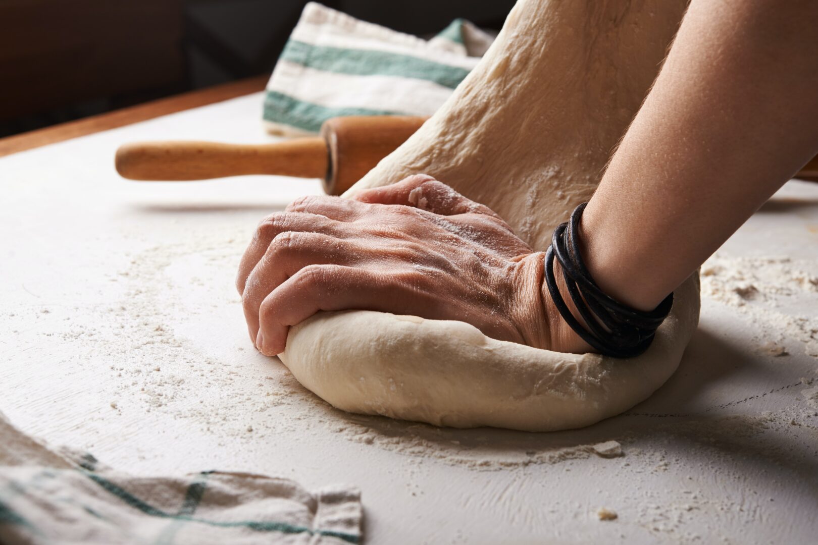 Pizzaioli bei der Arbeit: Hände die Pizzateig kneten.