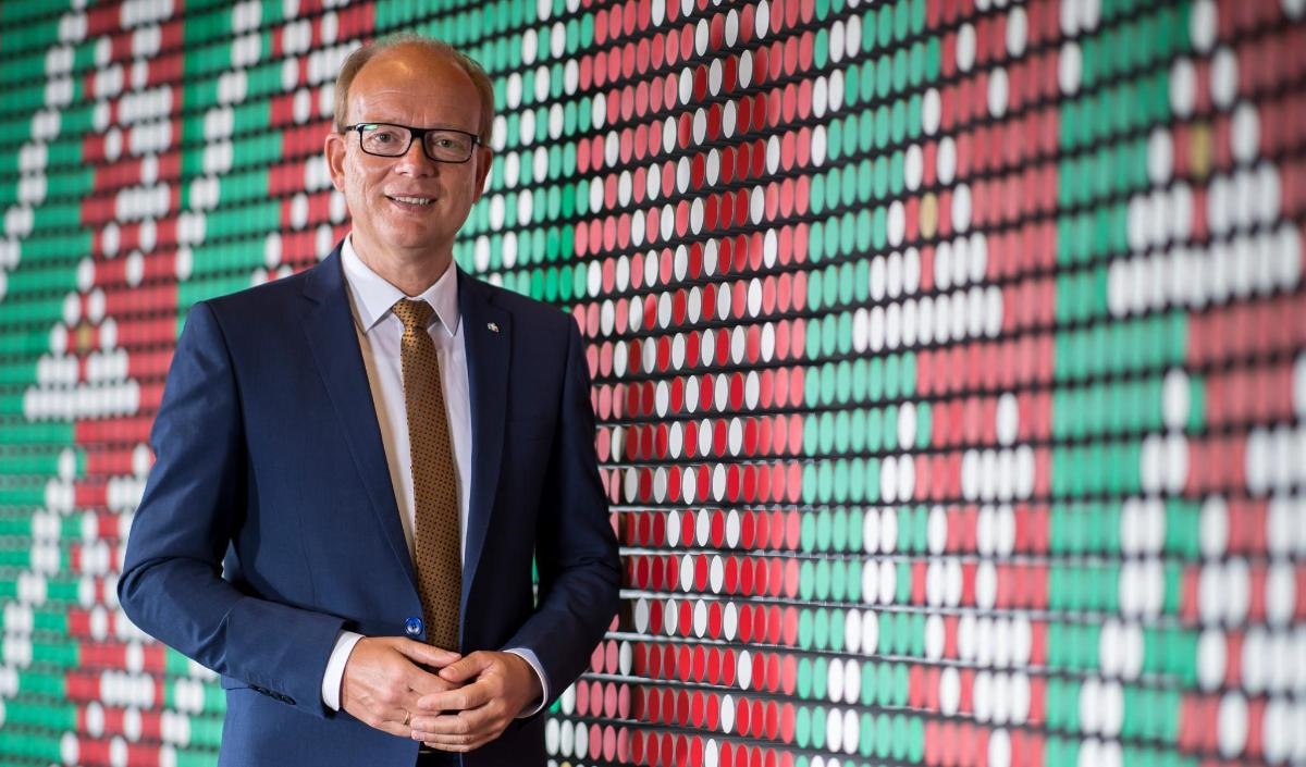 André Kuper, Präsident des Landtags NRW, steht vor einer Wand in grün-rot-weiß, den Farben NRWs.