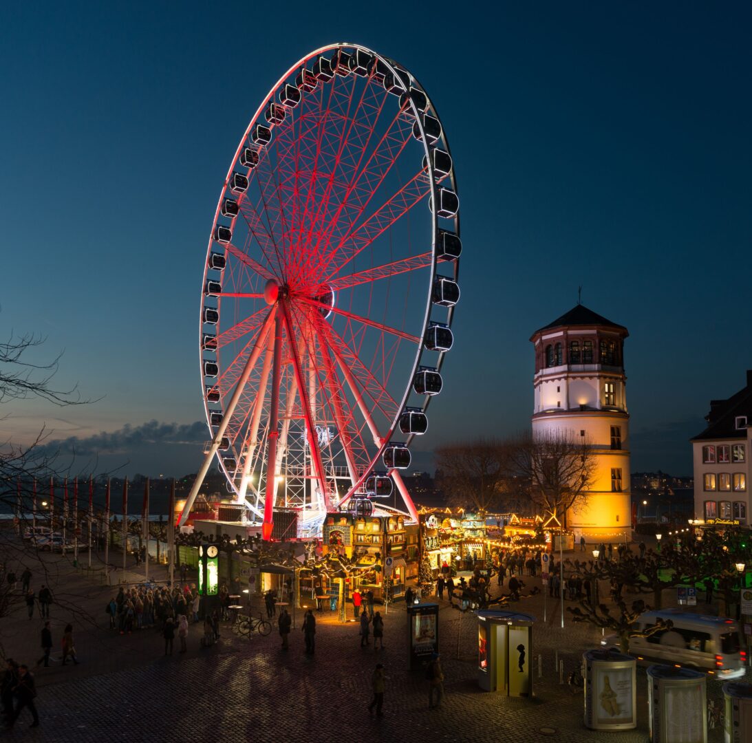 Rot und Blau erleuchtetes Riesenrad am Burgplatz in Düsseldorf.