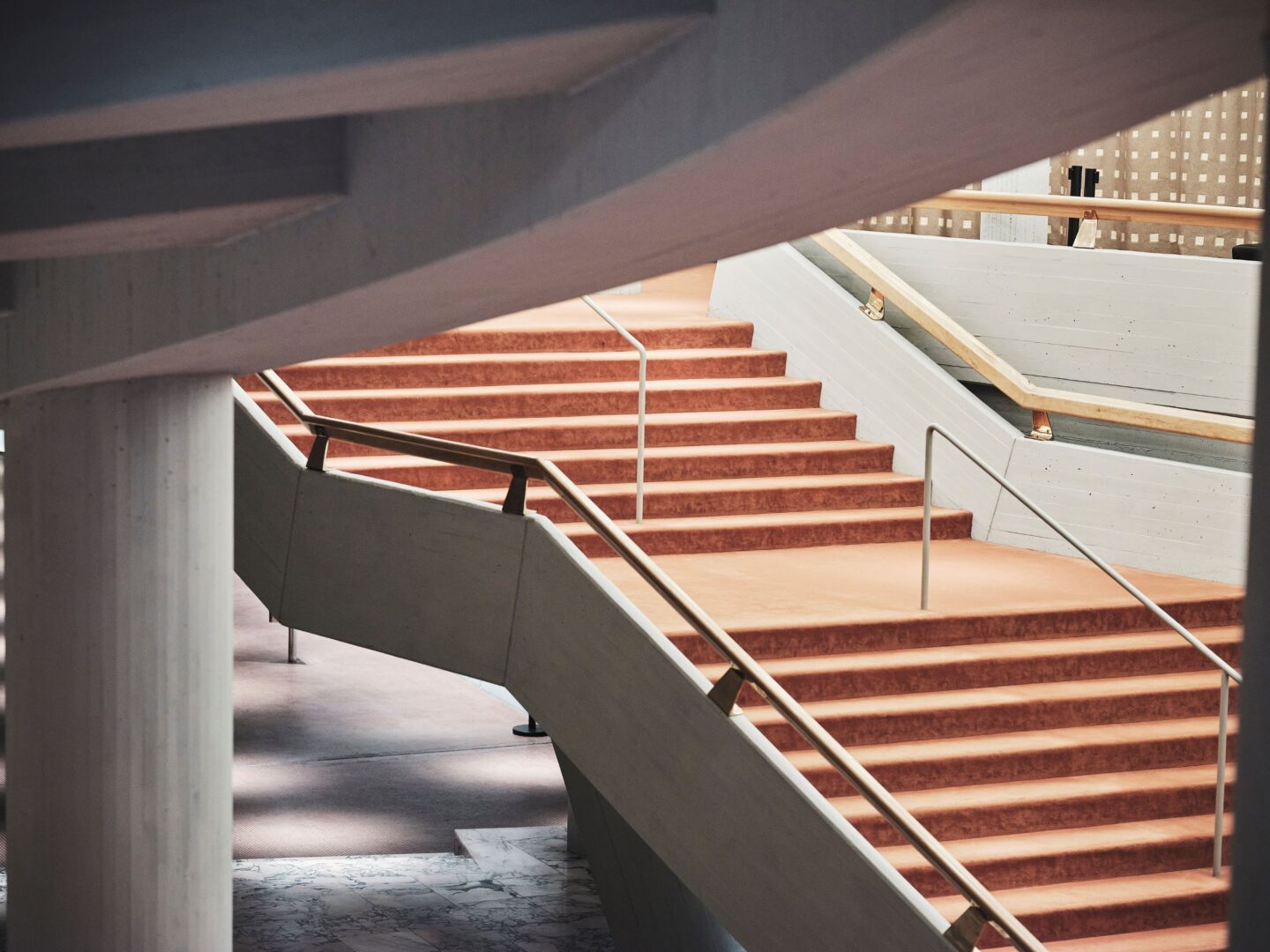 Ein Auschnitt der Treppe im Schauspielhaus. Farbfoto., die Stufen sind mit orangenem Teppich bezogen.