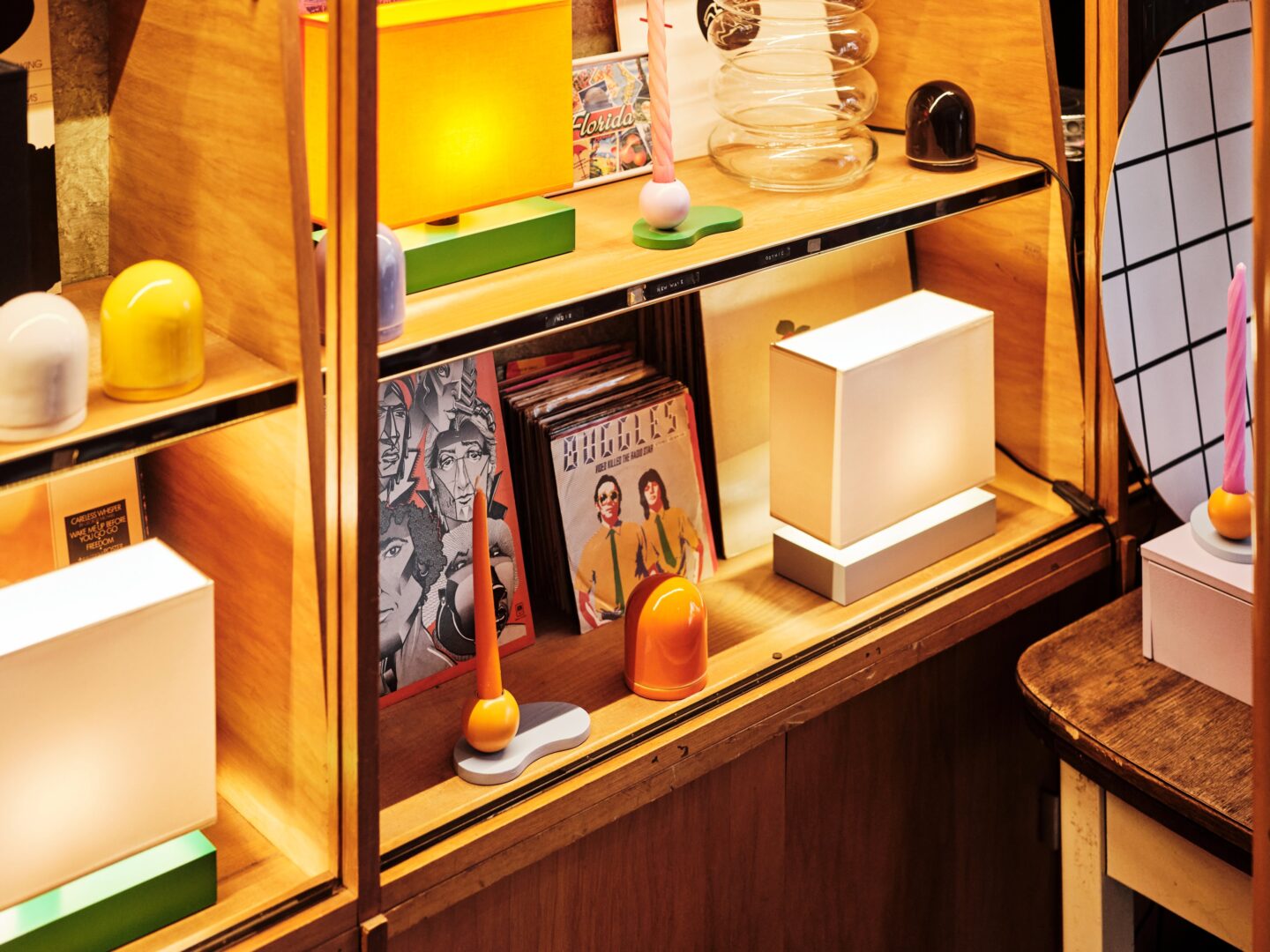 Blick von oben in ein Regal, indem Kerzen, Vinylsingles und Leuchten stehen.