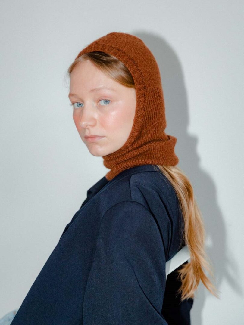 Frauenportrait, sie trägt eine dunkelblaue Jacke und ein rostrotes Balaclava.
