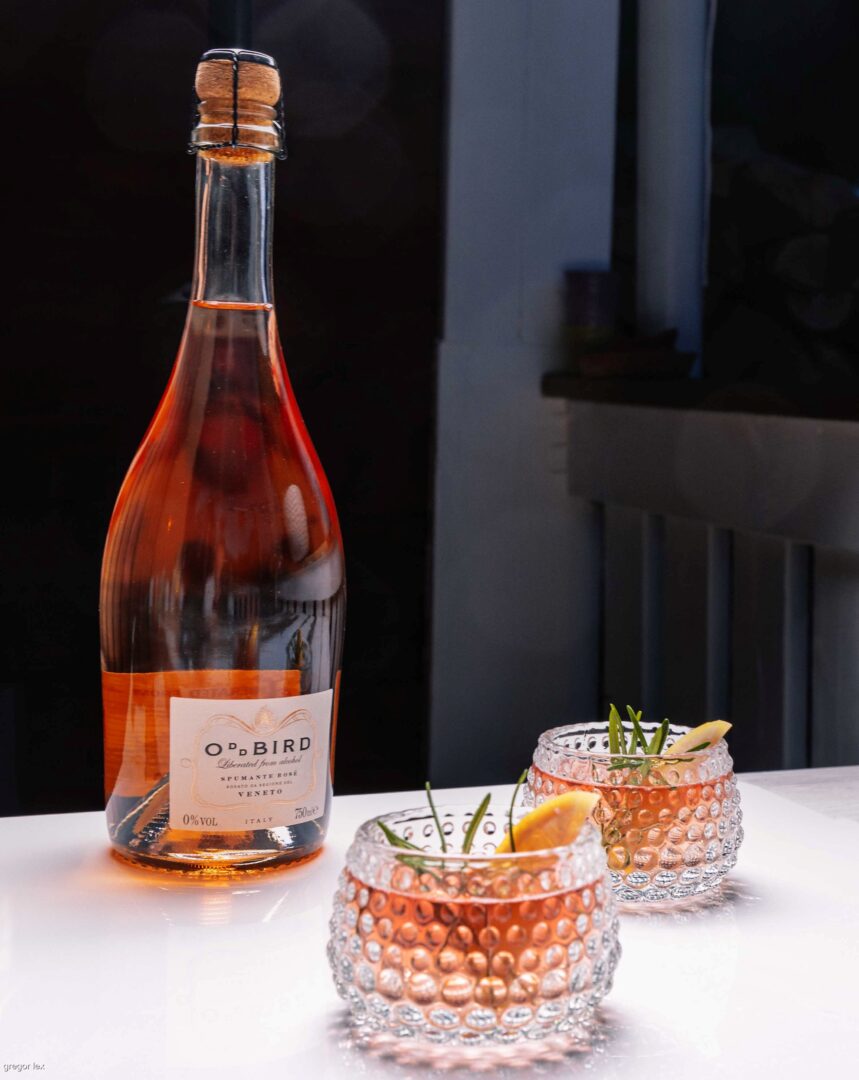 Flasche mit alkoholfreiem Rosé-Spumante und zwei Gläser. 