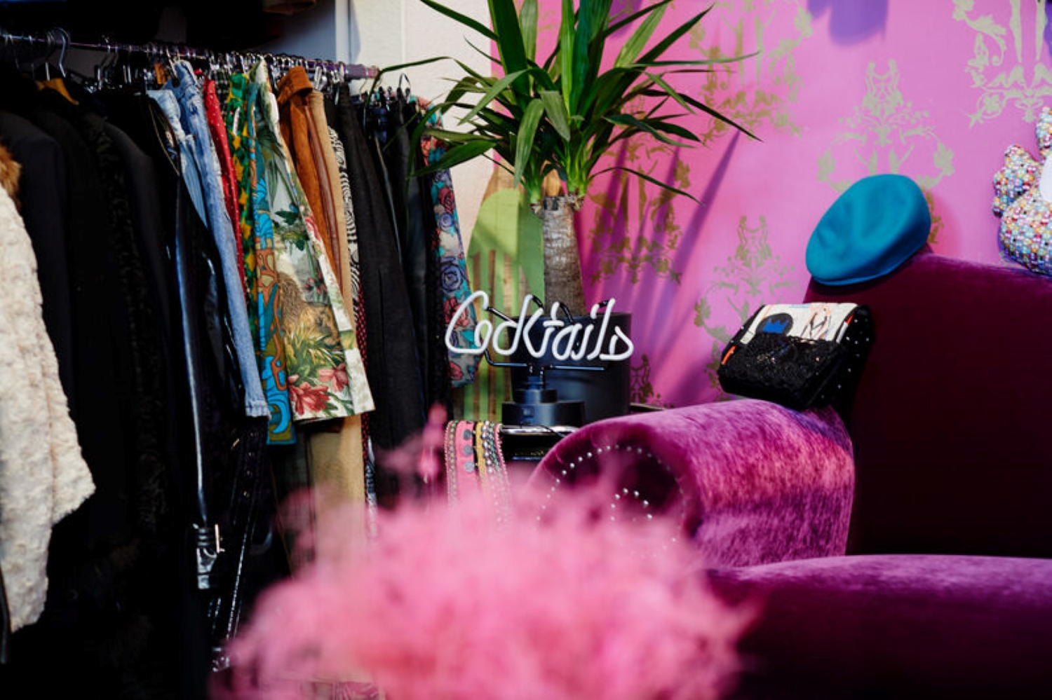 Im Vintage Store Elementarteilchen, man sieht eine pinke Federboa und viele Second Hand Sachen an einer Kleiderstange