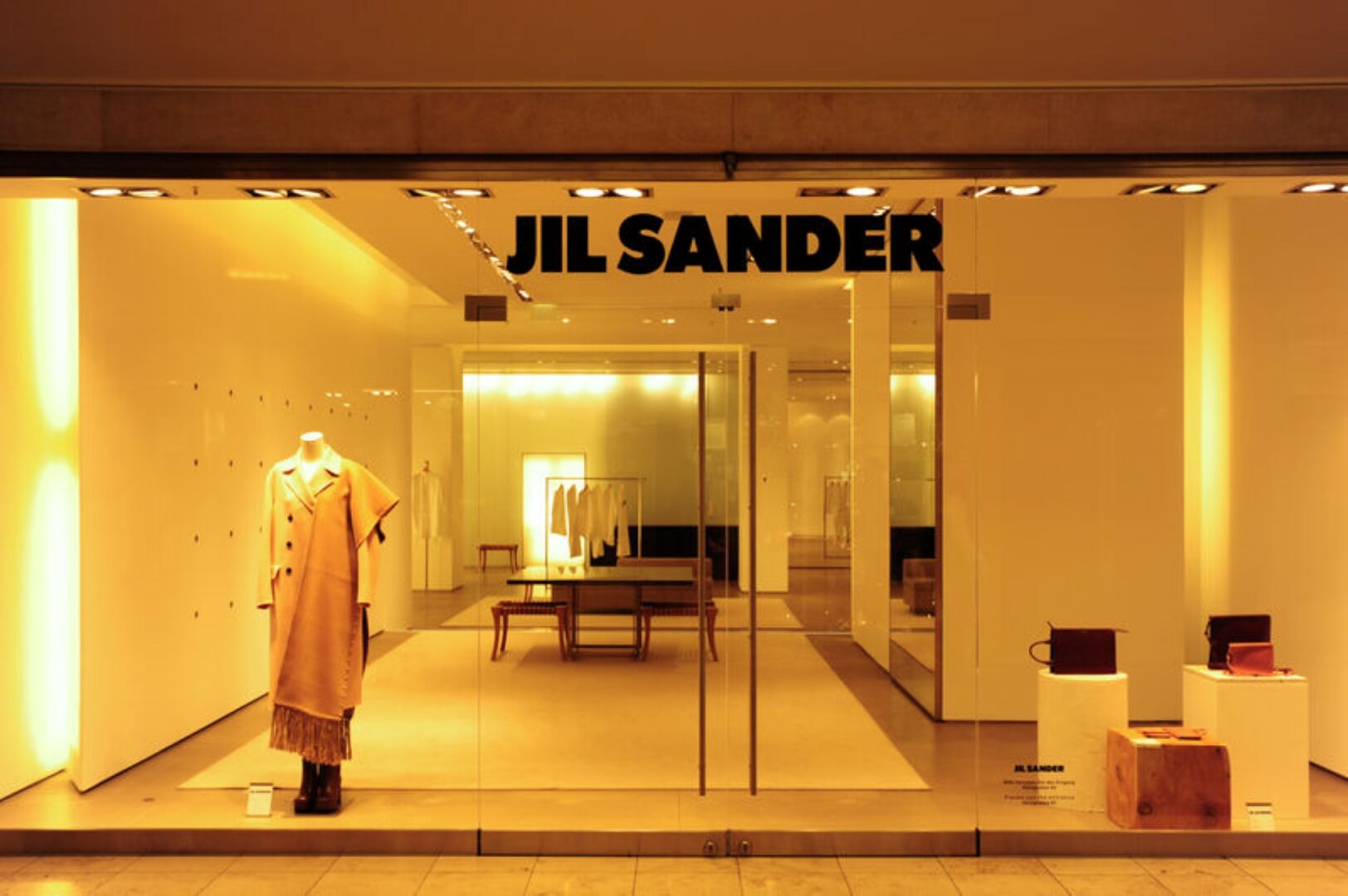 Das Schaufenster von Jil Sander in warmes Gelb getaucht und mit nur einem Look im Fenster. 