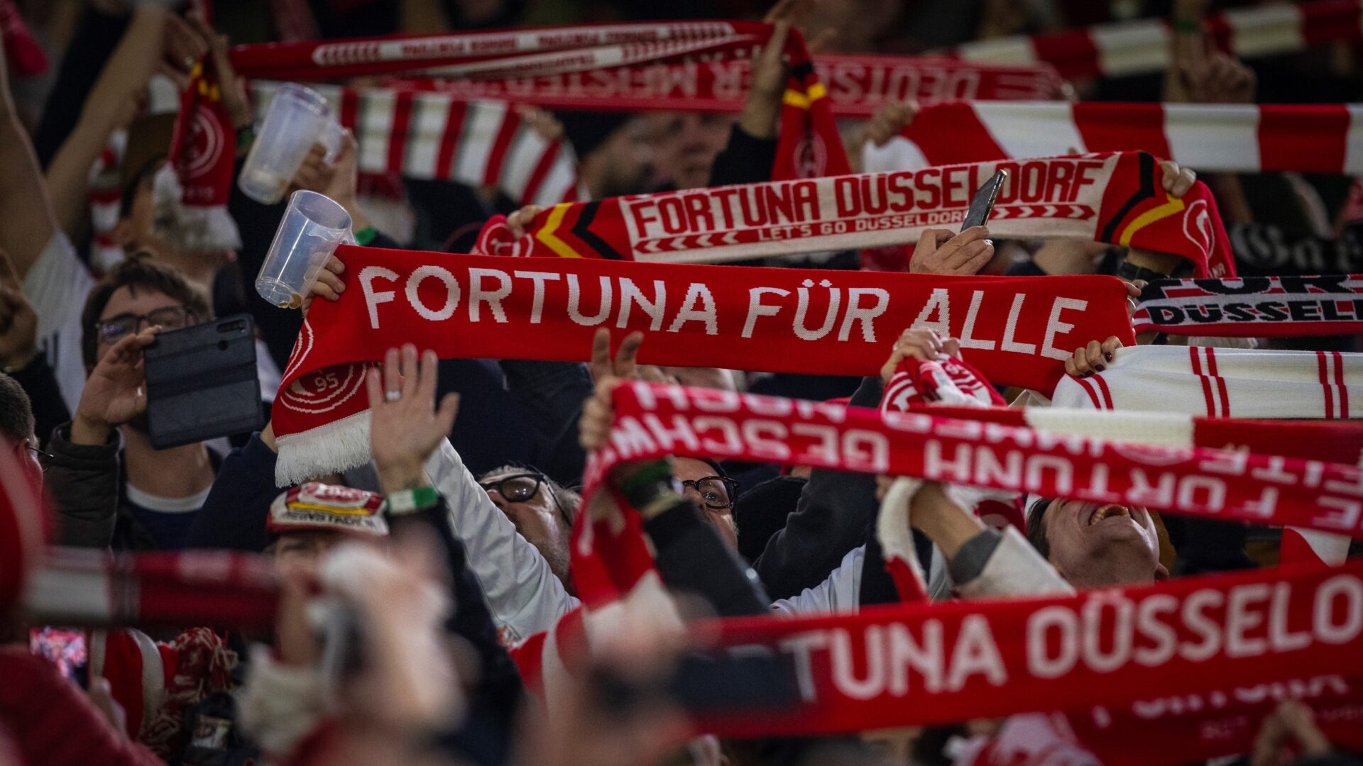 Man sieht wie Fans ihre Fanschals hochhalten, auf denen steht "Fortuna für alle".