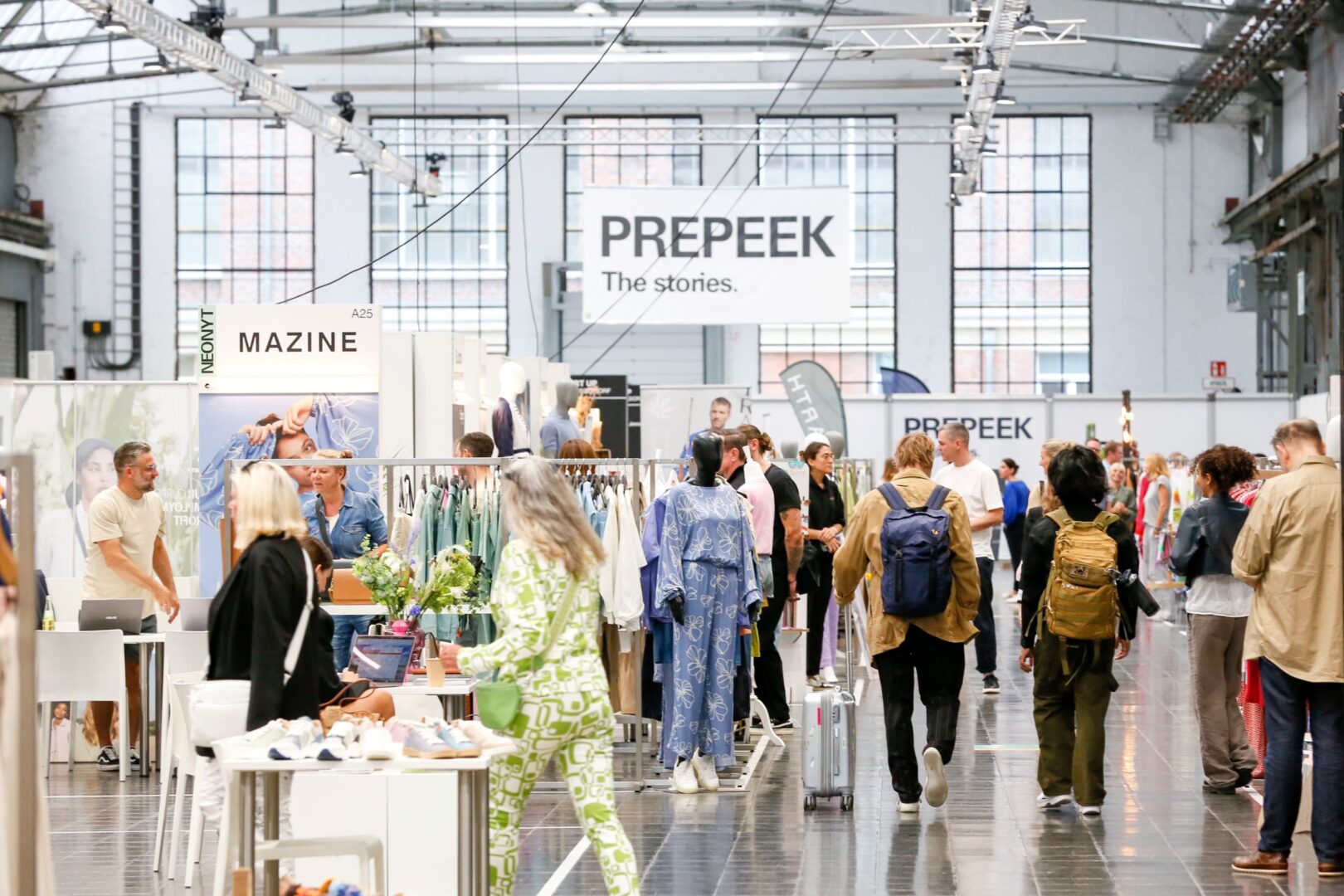 Aufnahme von der gut gefüllten Messehalle, man sieht Messebesucher:innen und Stände.