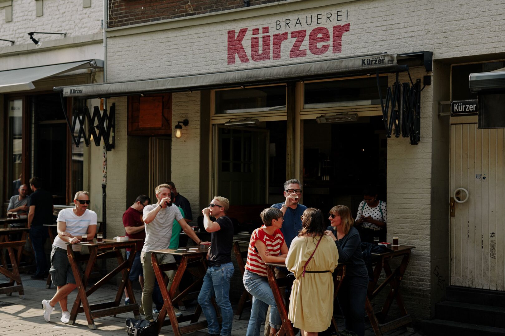 Eine Gruppe steht vor dem Kürzer in der Altstadt und trinkt Bier.