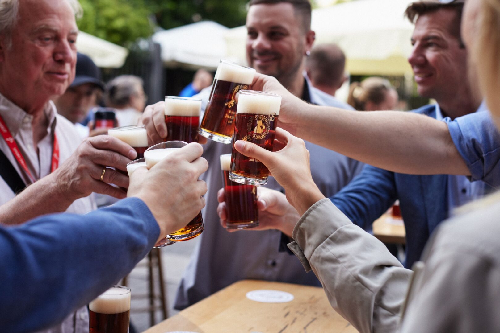 Man sieht Männerhände, die mit je einem Glas Altbier anstoßen.