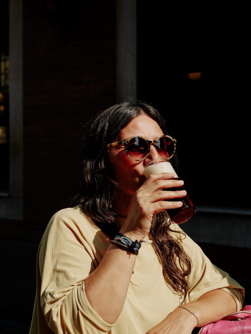 Frau mit Sonnenbrille trinkt Altbier. 