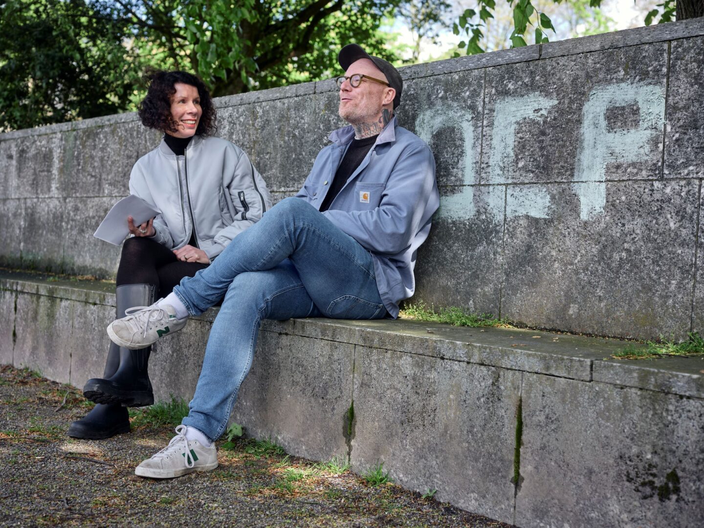 Ilona Marx und Tim Berresheim sitzen im Hofgarten auf einer steinernen Bank.