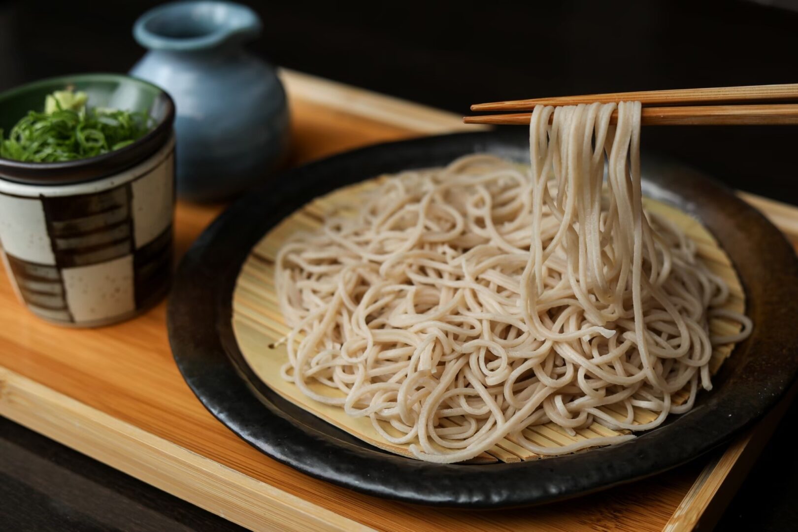 Soba-Nudeln angerichtet auf einem Teller, mit Stäbchen und Beilage.