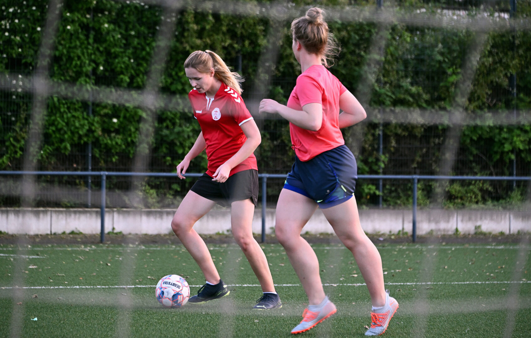 Frauenfußball: Zwei Spielerinnen spielen sich den Ball zu. 