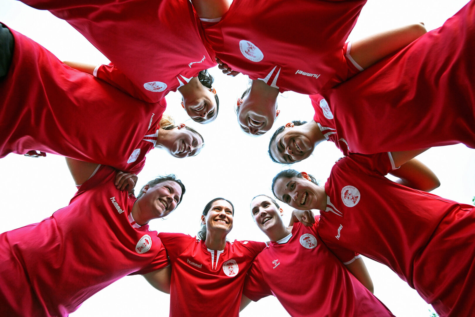 Frauenfußball in Düsseldorf: Rotweiß Blutgretchen stehen im Kreis, von unten fotografiert.