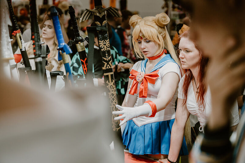 Eine Sailor Moon Cosplayerin an einem Messestand.