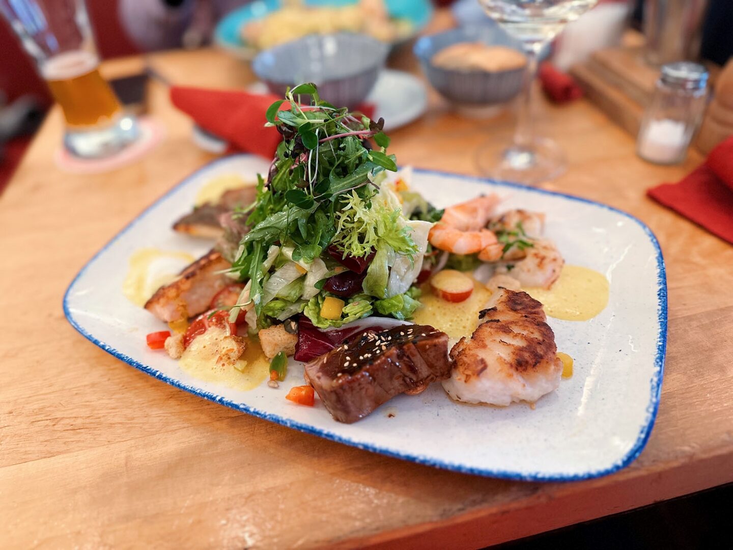 Ein Salat mit Fisch, angerichtet auf einem rechteckigem Teller.