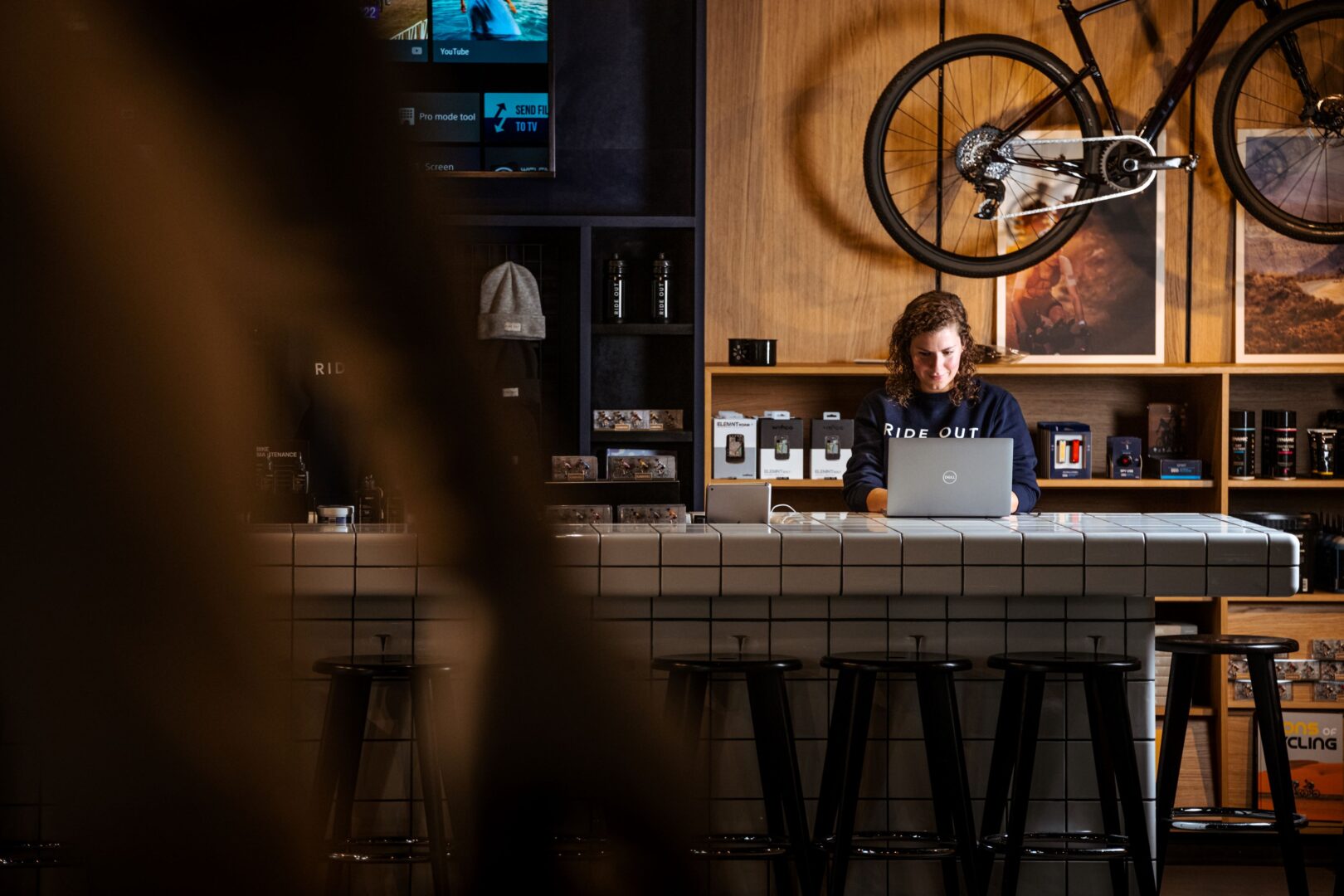 Maya hinter dem Counter Desk am Laptop im Fahrradladen Ride Out in Amsterdam. 