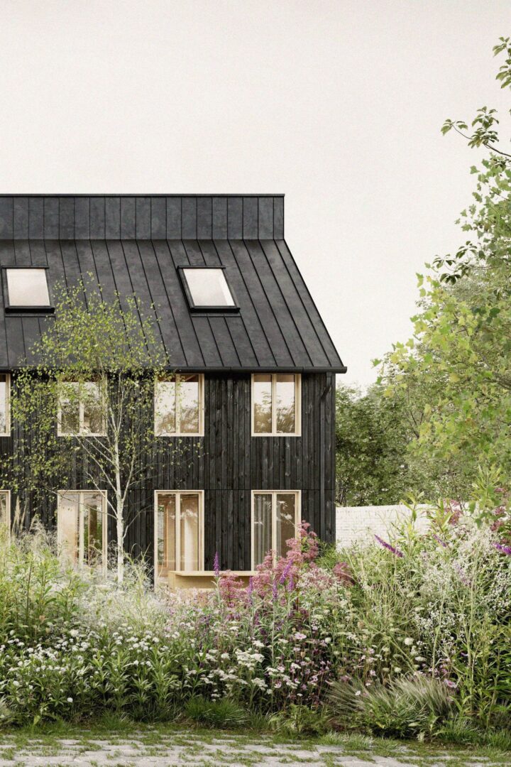 Man sieht ein dunkles Holzhaus mit vielen Fenstern, das teilweise hinter Büschen und Ästen verschwindet.