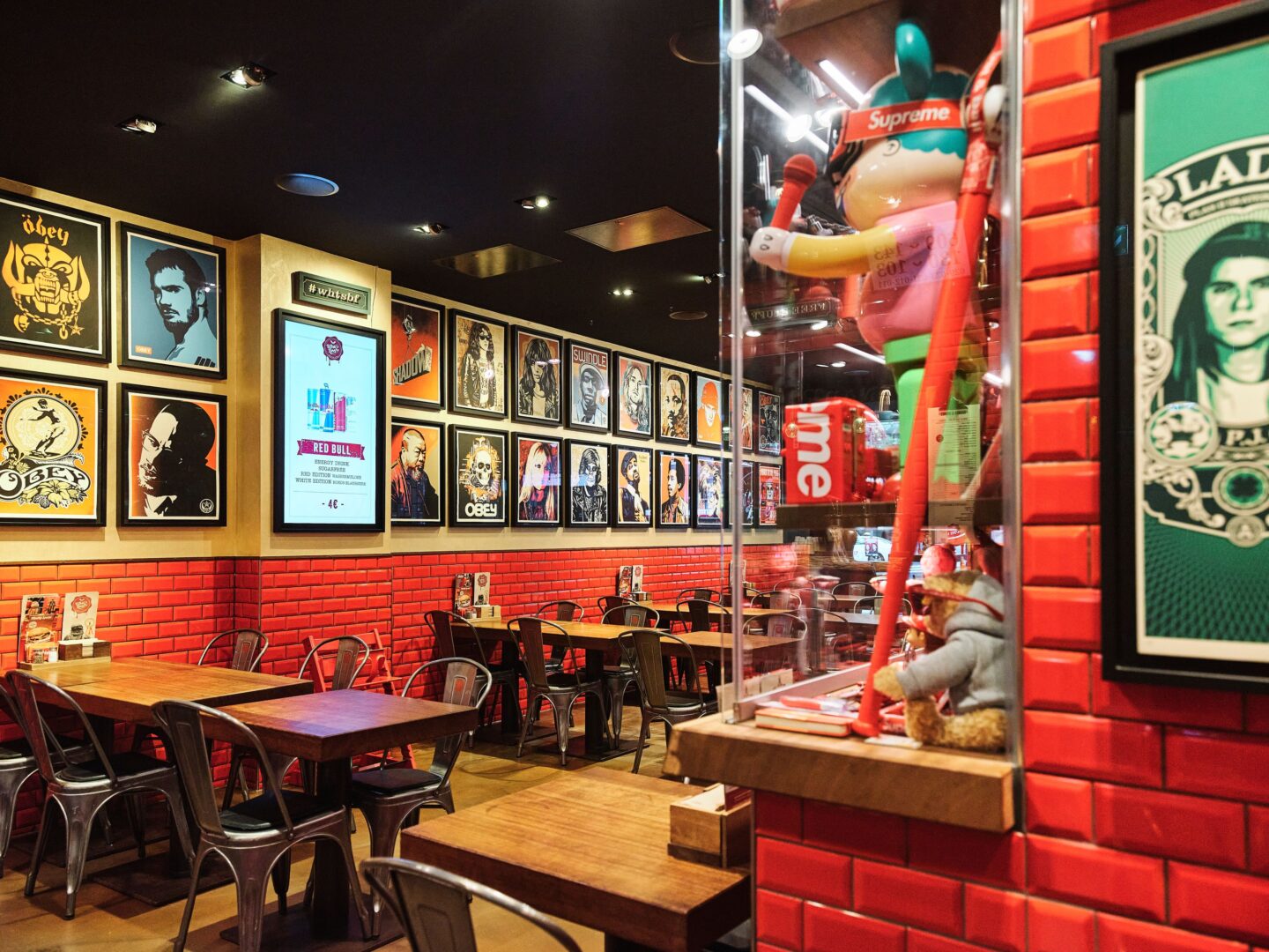 Interior im Burgerladen: Die Wände sind rot gekachelt, an den Wänden über den Tischen hängen Kunstdrucke à la Andy Warhol von Popstars und in Vitrinen sind zahlreiche Pop-Art und Toys ausgestellt.