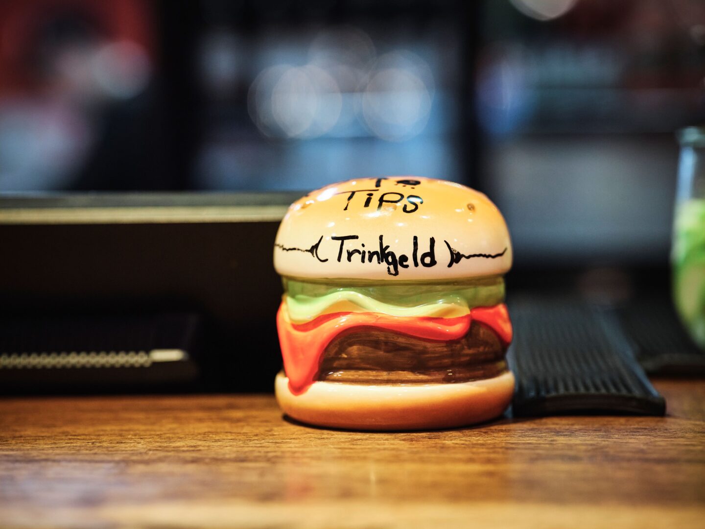 Spardose in Form eines Burgers, obendrauf steht handgeschrieben : Trinkgeld.