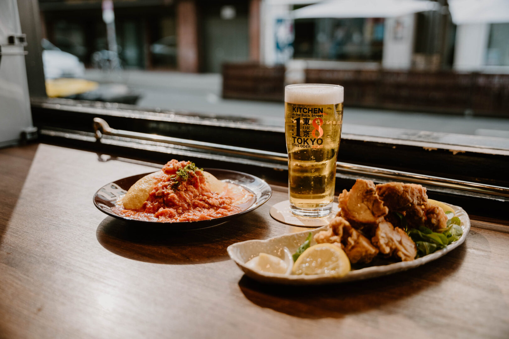 Man sieht zwei Teller mit japanischem Essen und ein Glas Bier.