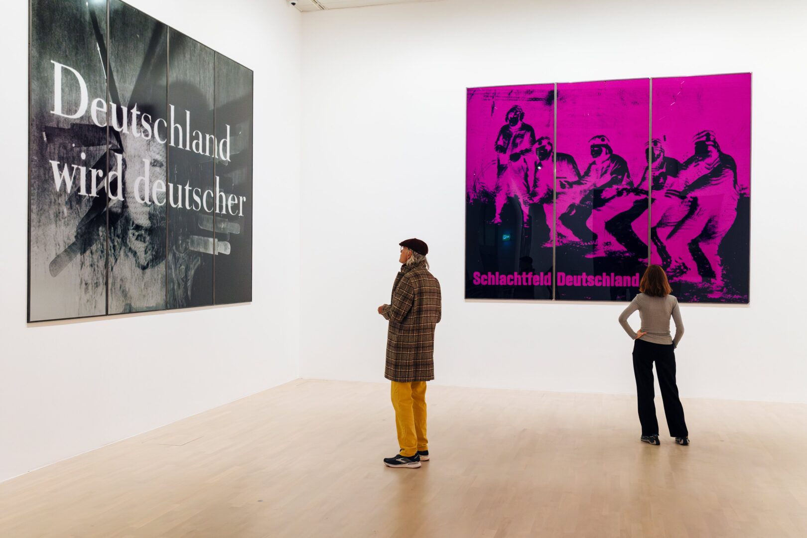 Installationsansicht: links ein Foto mit der Aufschrift: Deutschland wird deutscher. Rechts: schwarz-magenta, man sieht Soldaten. Aufschrift: Schlachtfeld Deutschland.