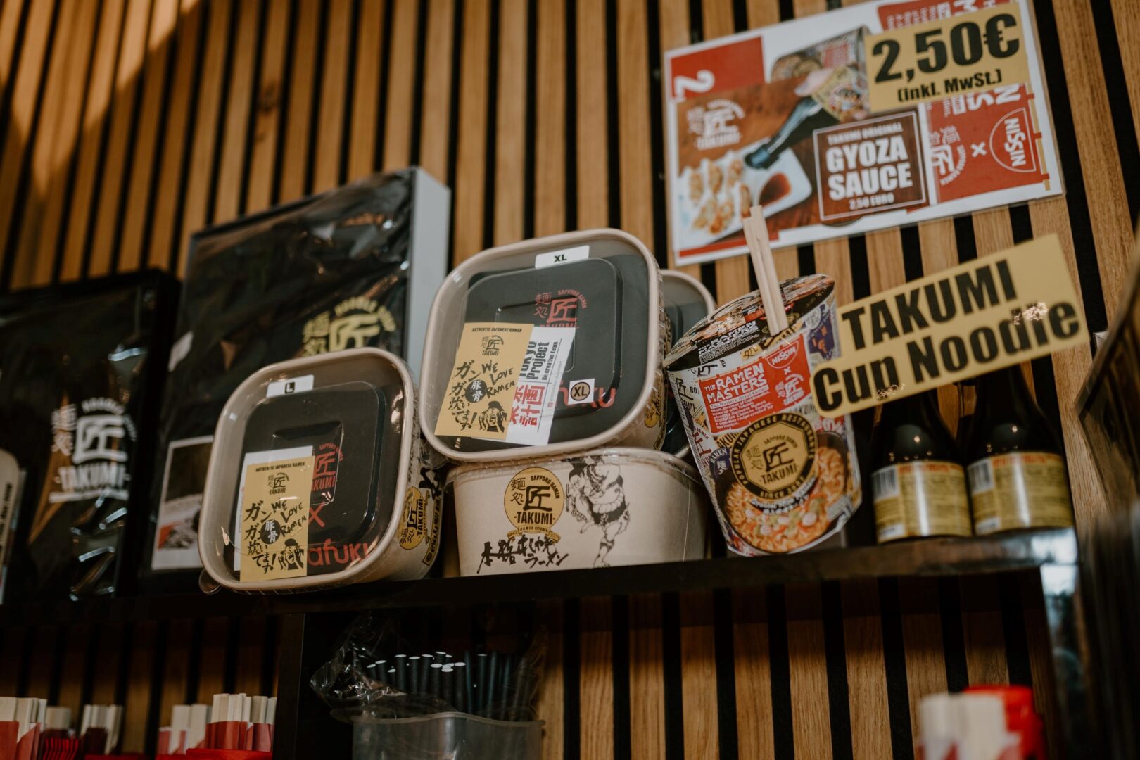 Man sieht auf einem Regalbrett Cup Noodles von Takumi.