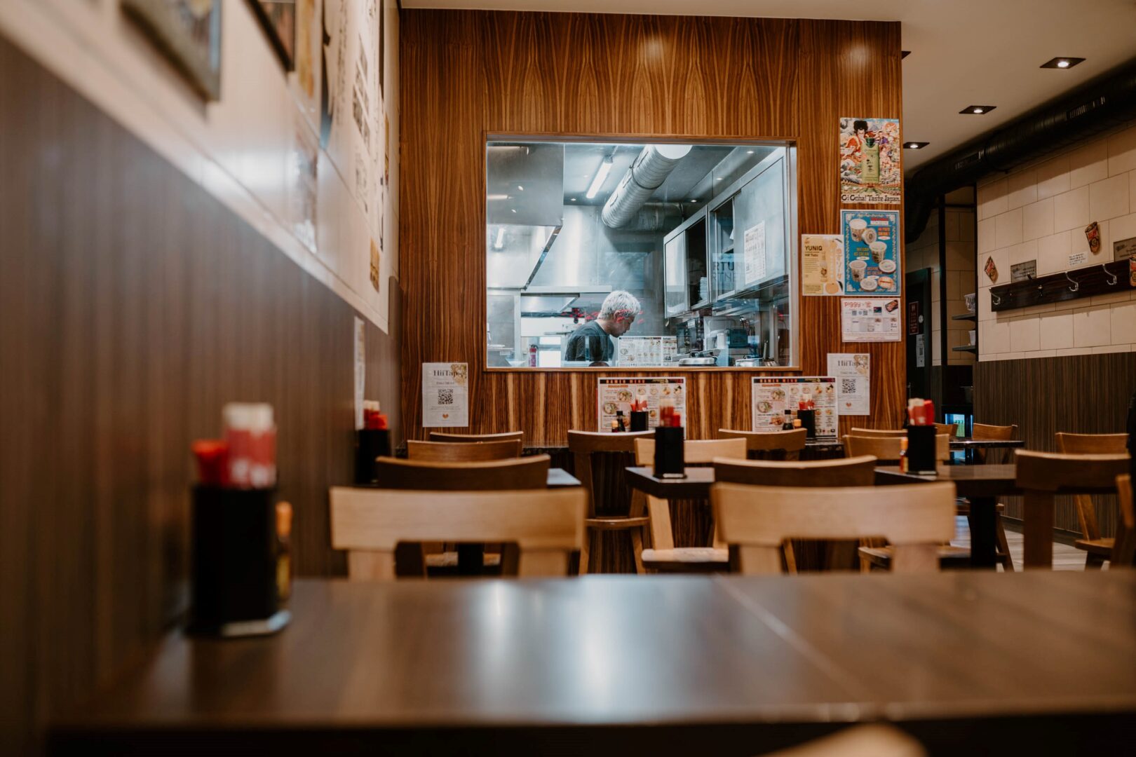 Das Restaurant Takumi 1st: Man sieht im Vordergrund die Tische und hinten durch eine fenstergroße Öffnung die Küche.