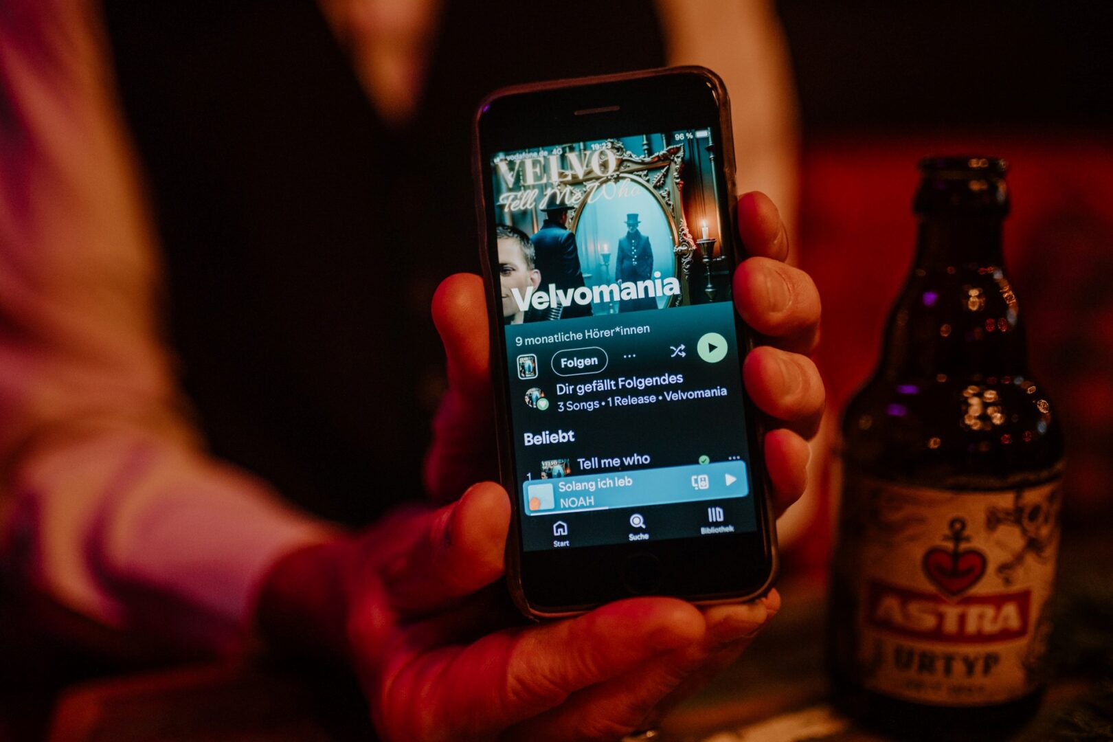 Mayo hält sein Handy in der Hand, auf dem Display sieht man seine Playlist "Velvomania".