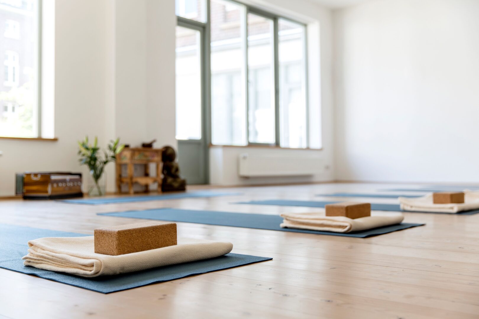 Ein Yogastudio mit hellem Holzboden. einheitlich blaue Yogamatten ausgestattet mit Decke und Yogaklotz.