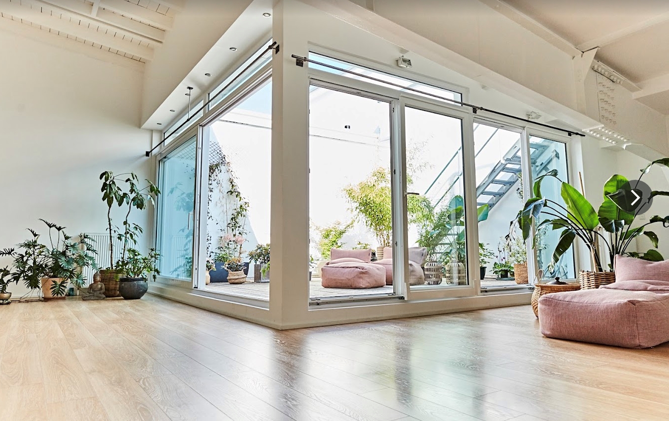 EinYogastudio im Dachgeschoss mit hohen Decken und einer großen bepflanzten Dachterrasse.