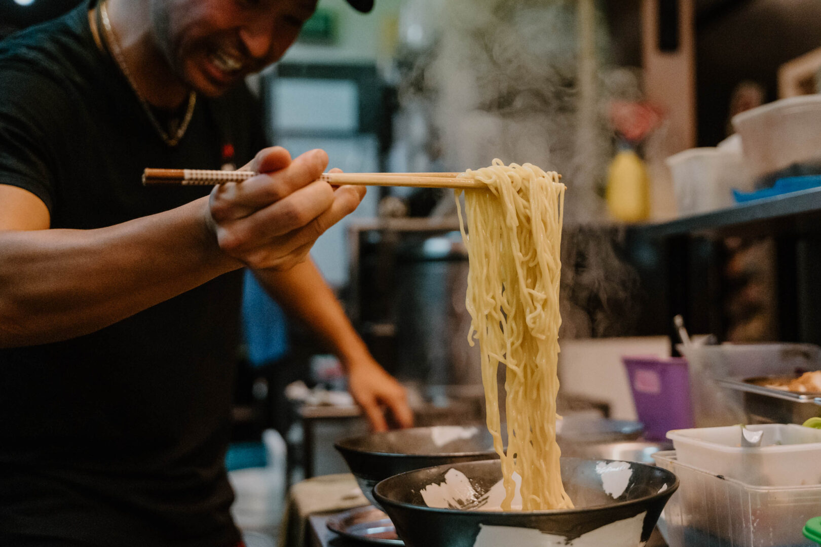 Man wirft einen Blick in die Küche eines japanischen Restaurants und sieht wie der Koch Ramen zubereitet.