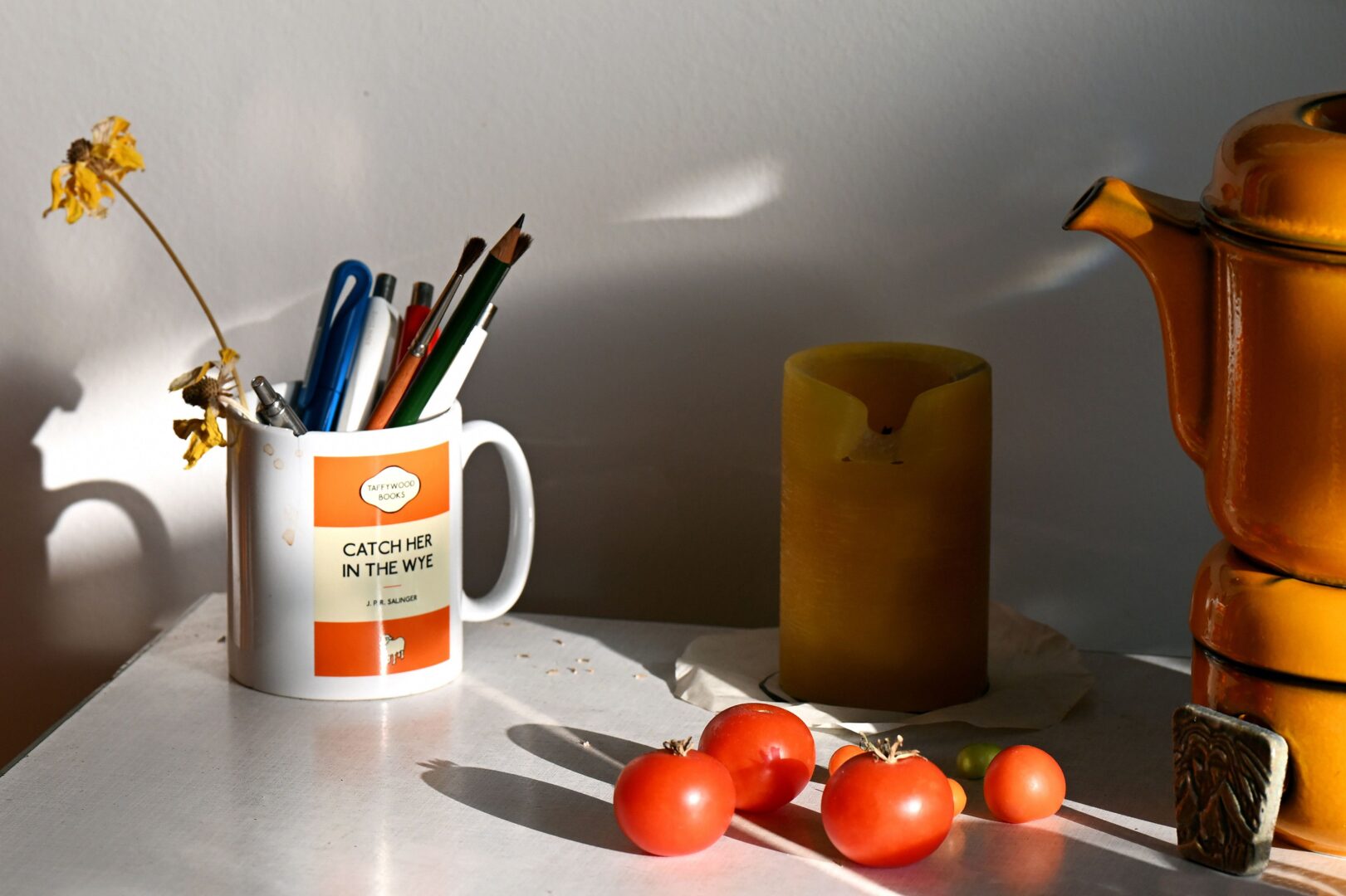 Stillleben von Mithu Sanyals Küchentisch. Man sieht einen Kaffeebecher, in dem Stifte stehen und Tomaten.
