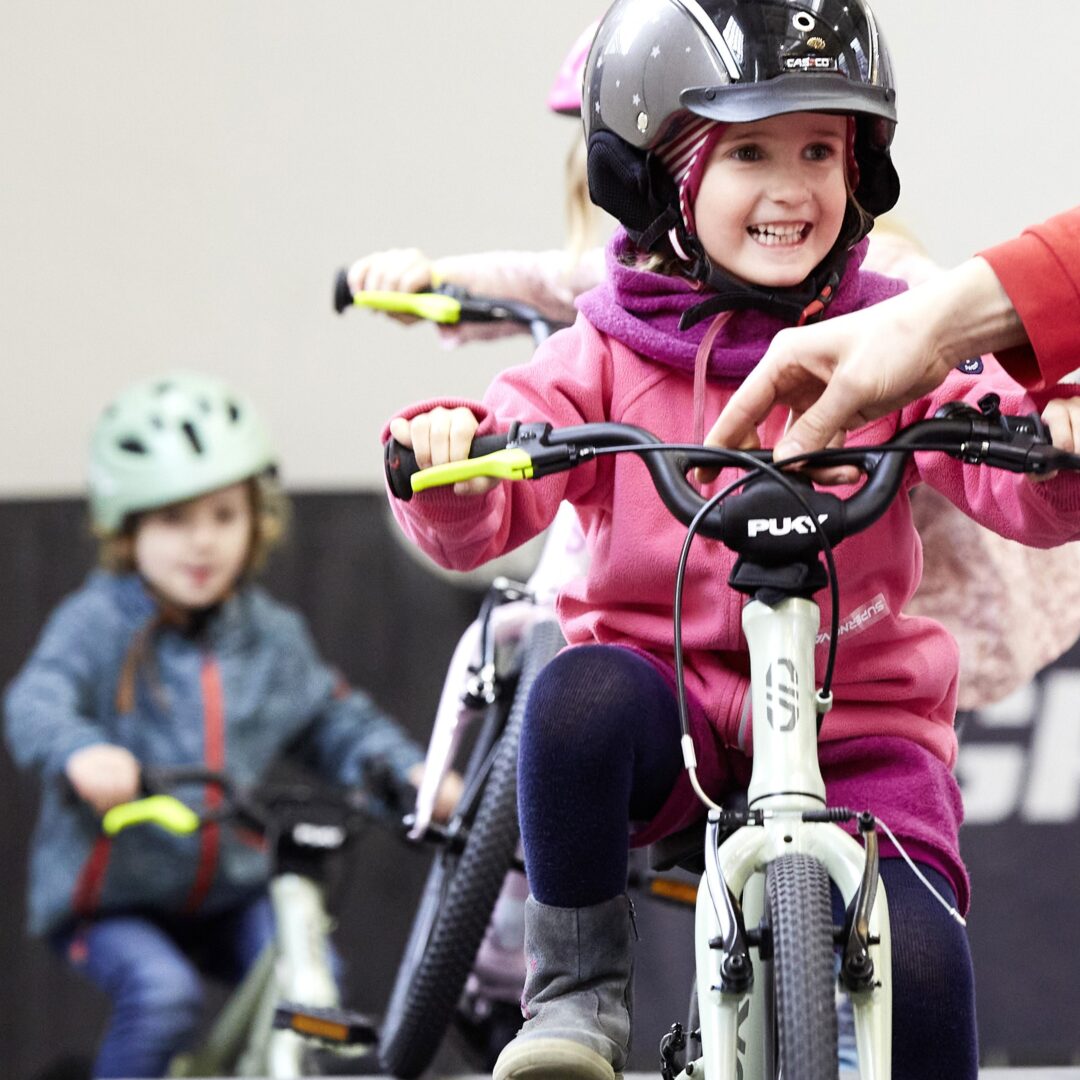 Ein Kind mit Fahrradhelm probiert ein Kinderrad aus. 
