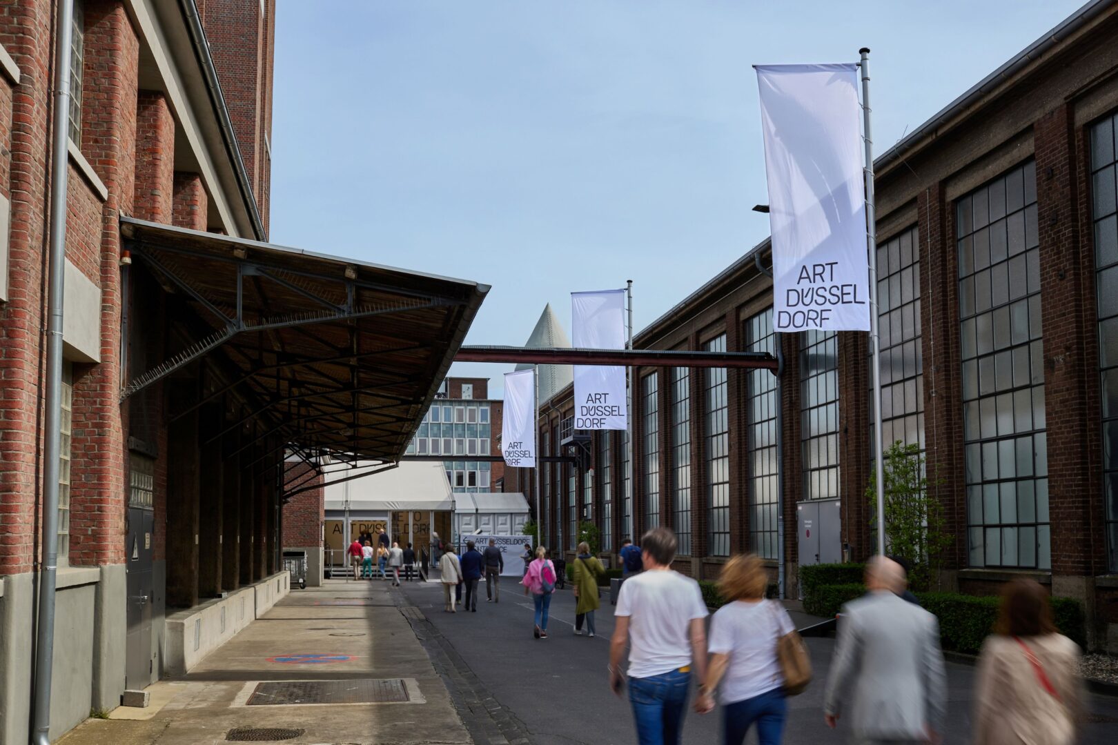 Man sieht Menschen zwischen zwei Industriehallen auf dem Areal Böhler, wo die Art Düsseldorf stattfindet.