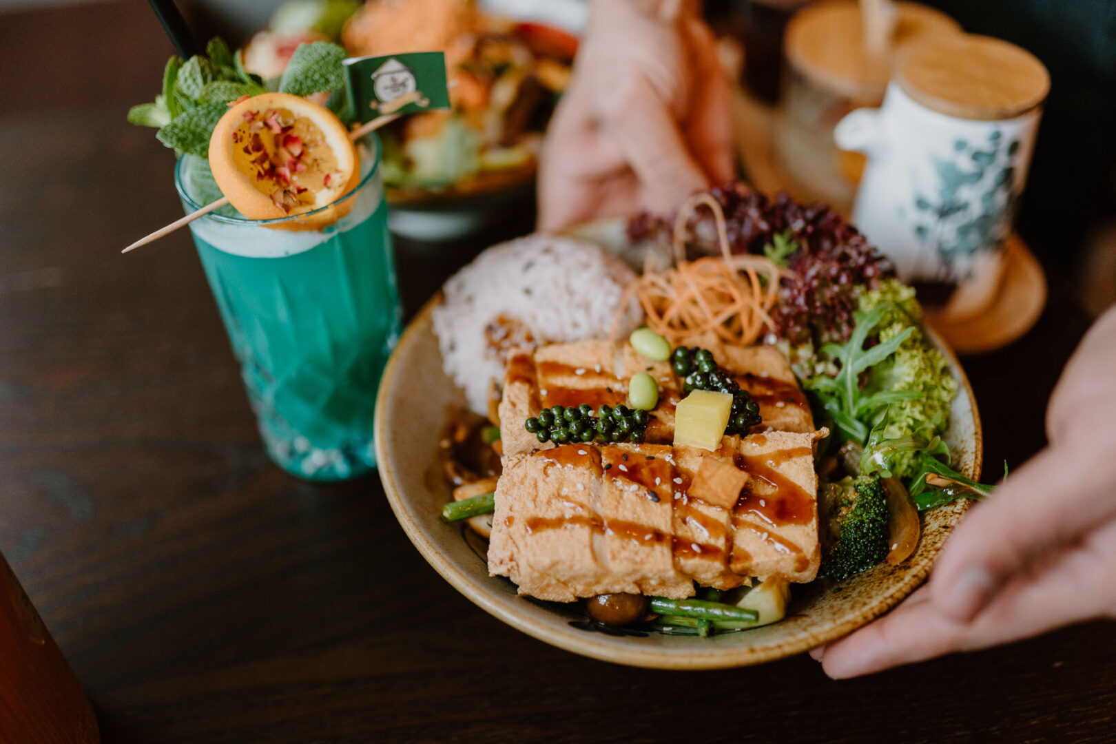 Vegane Restaurants boomen. Hier sieht man ein veganes Tofugericht mit viel Gemüse und einen türkisfarbenen Cocktail.