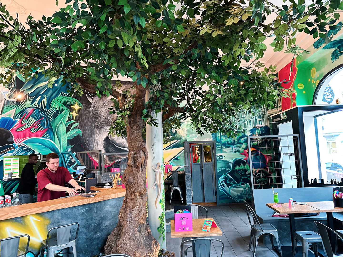 Vegane Restaurants haben oft ein besonderes Ambiente. Wie hier Urban Gorillaz, wo der Name die Einrichtung inspiriert hat. Man sieht einen Baum mitten im Lokal und bunte Graffiti. 