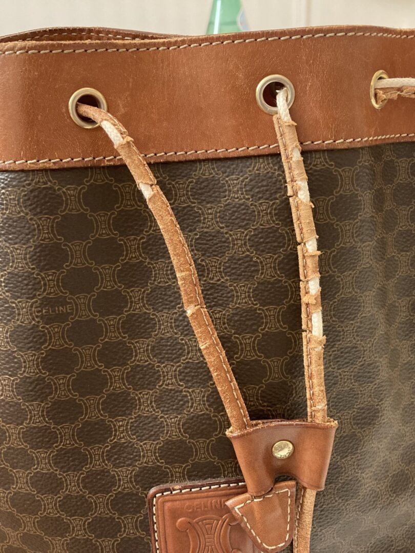 Detailaufnahme eines Lederbandes, das eine Tasche zusammenzieht und kaputt ist. 