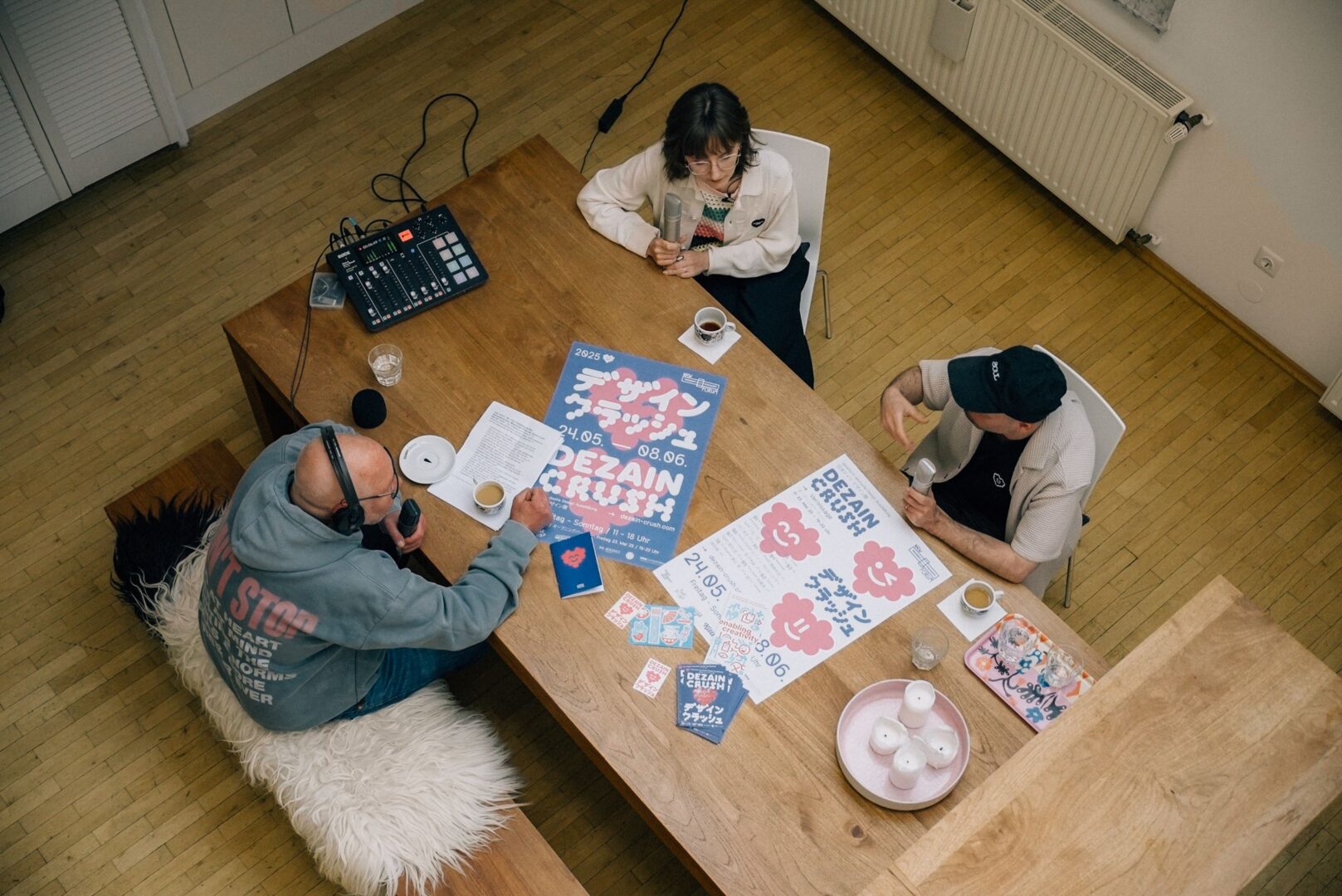 Aufnahme von oben, man sieht drei Personen an einem Tisch sitzen.