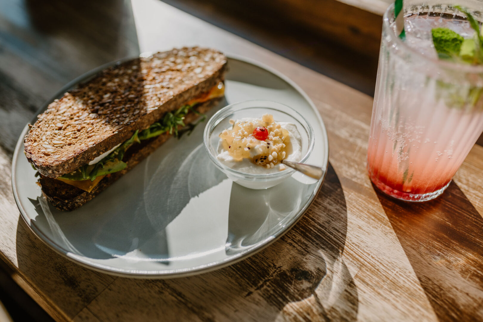 Man sieht einen Teller mit einem Vollkornbrotsandwich und ein Glas mit einer hausgemachten Limonade.