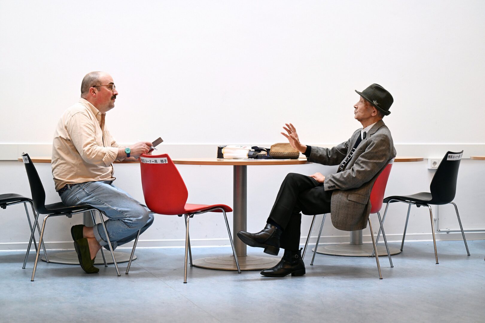 Clemens Henle, der Autor, im Interview mit Herrn Takeda (rechts). Beide sitzen sich an einem Tisch gegenüber.