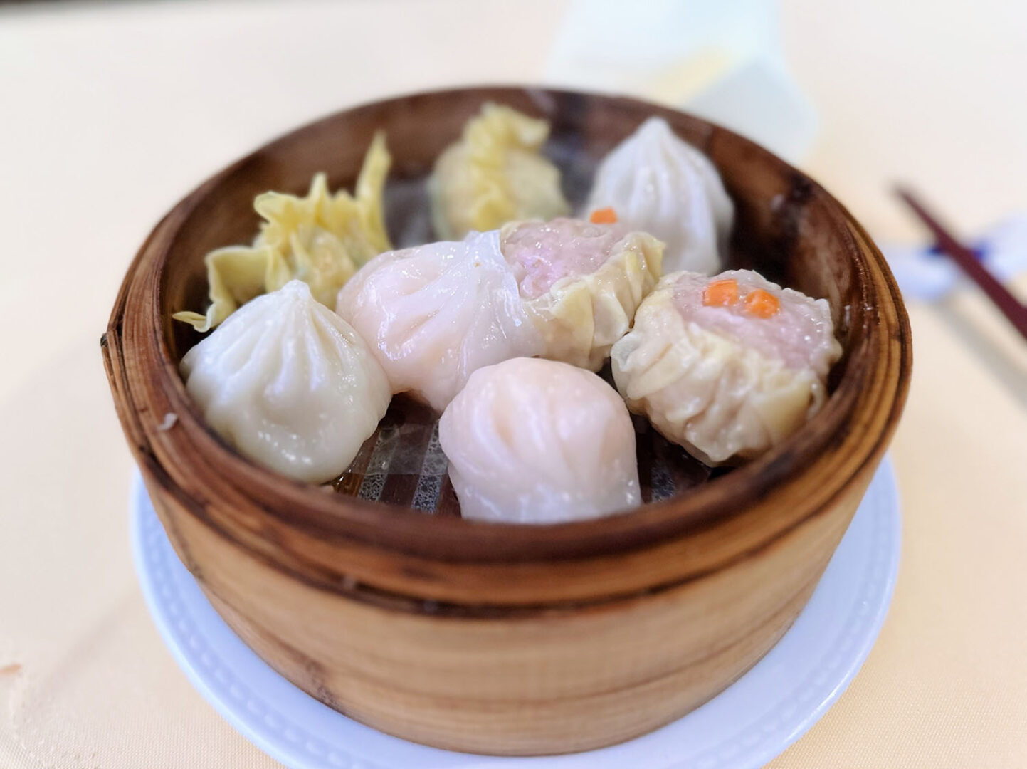 Man sieht einen typischen Bambuskorb zum Dampfgaren, in dem mehrere Dim Sums sind.