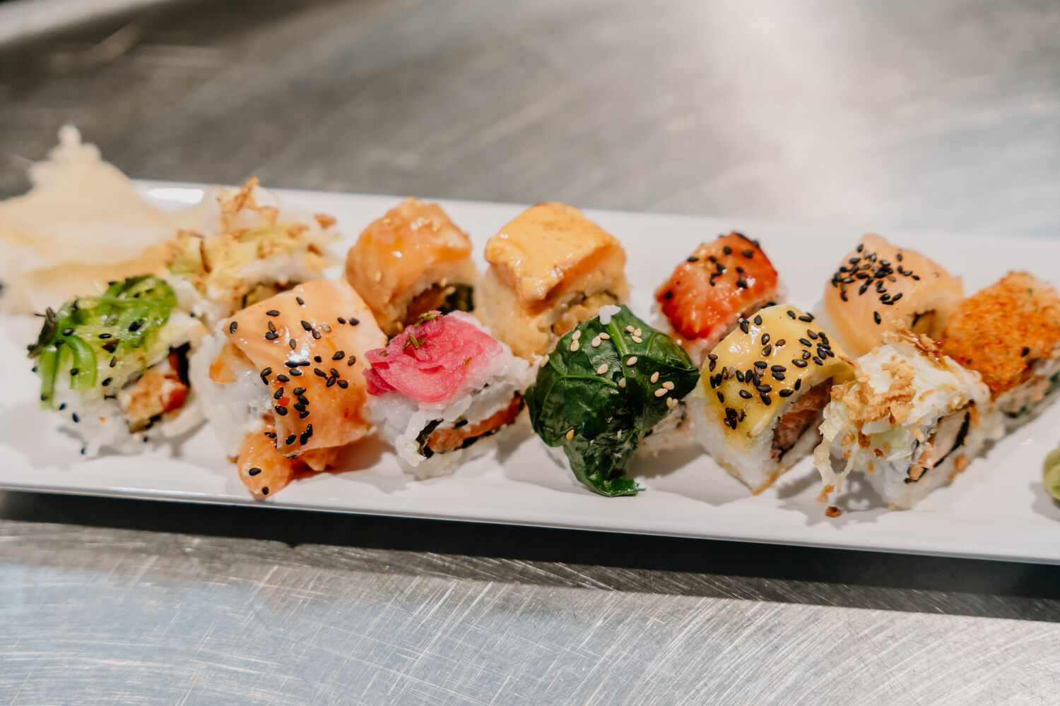 Man sieht 12 Sushi Rollen, die alle unterschiedlich gefüllt und dekoriert sind.