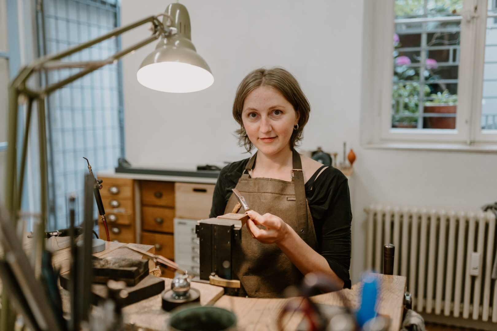 Mitinhaberin Lisa sitzt am Arbeitstisch in der Werkstatt und bearbeitet einen Ring.