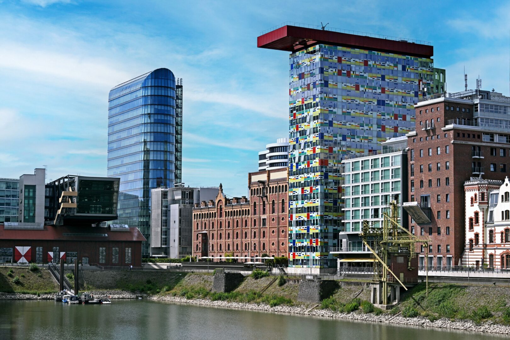 Man sieht sehr moderne Hochhäuser zwischen alten Backsteingebäuden des Hafens in Düsseldorf. 