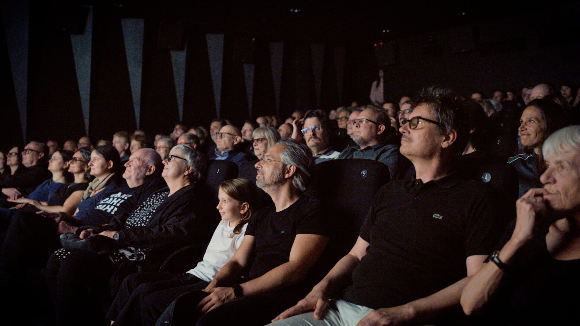 Man sieht das Publikum im Kino Black Box in den Sitzreihen auf die Leinwand schauend.