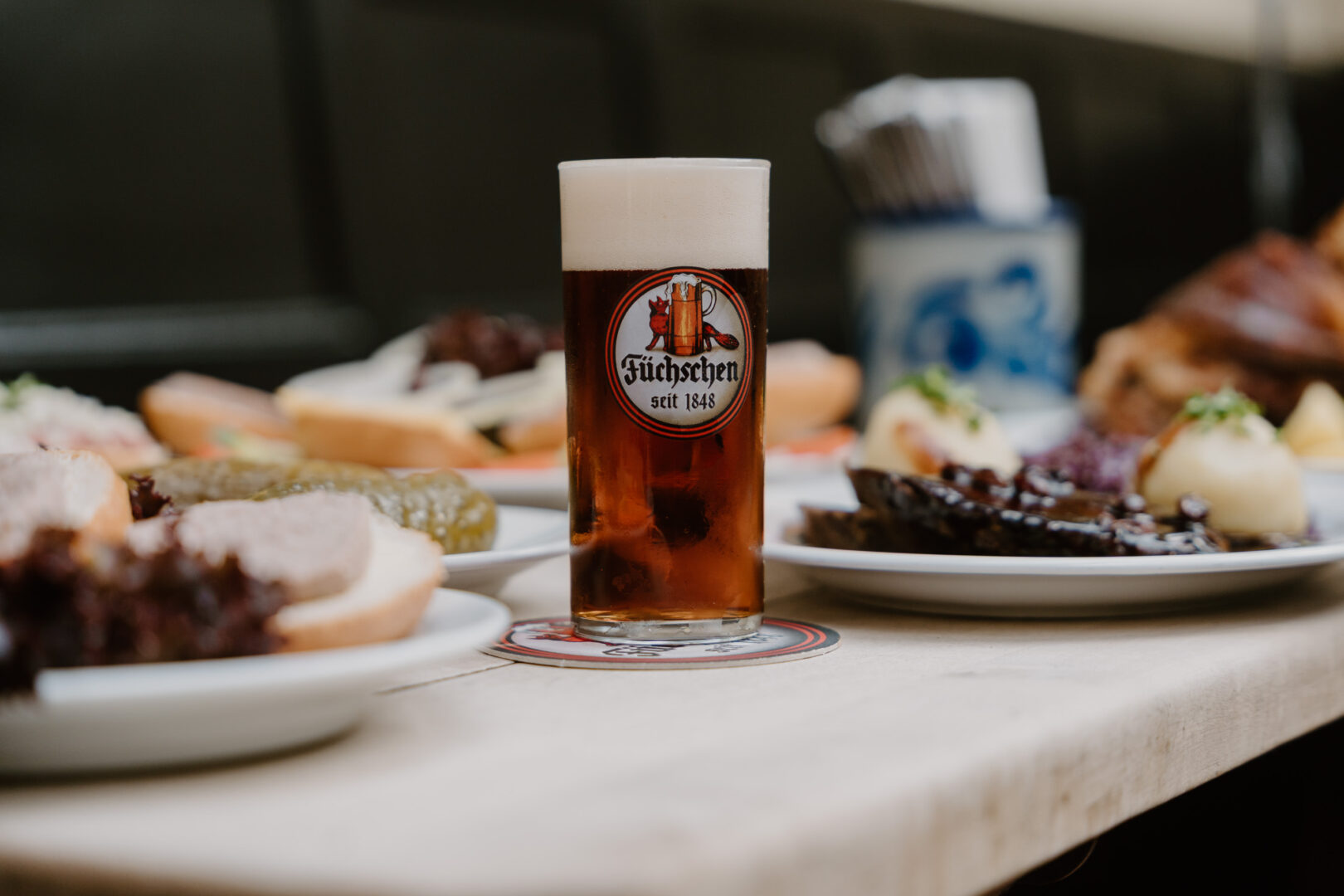 Ein volles Altbierglas steht auf einem gedeckten Tisch mit Brauhausessen.
